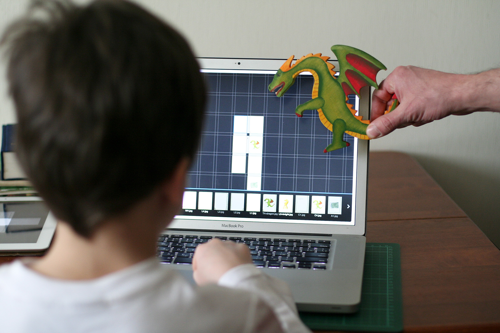 Parent and child collaborating on creating digital stories together, with a dragon illustration on the screen